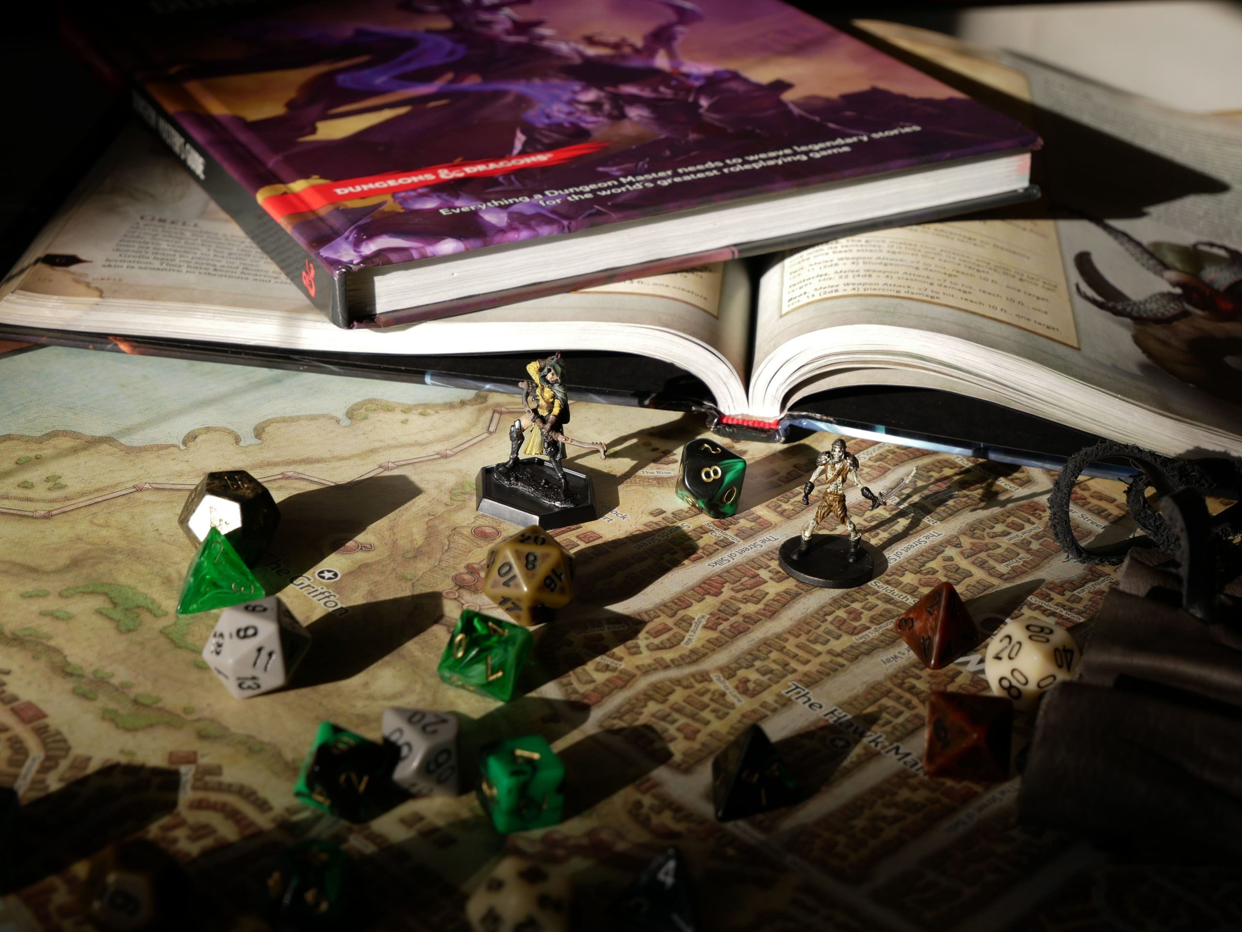 Fantasy tabletop role-playing setup with dice, miniatures, rulebooks, and a map